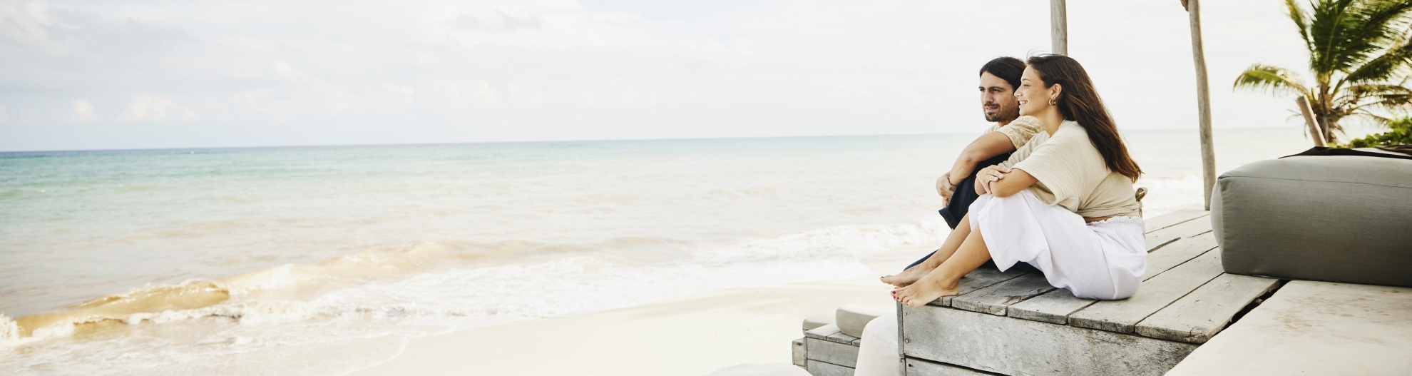 Couple Sitting In Tropical Lounge Overlooking Beach